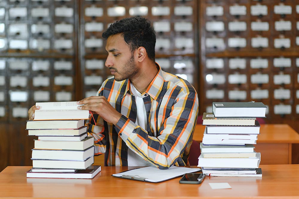 Real life Bibliometric analysis - male examining two similarly sized piles of books
