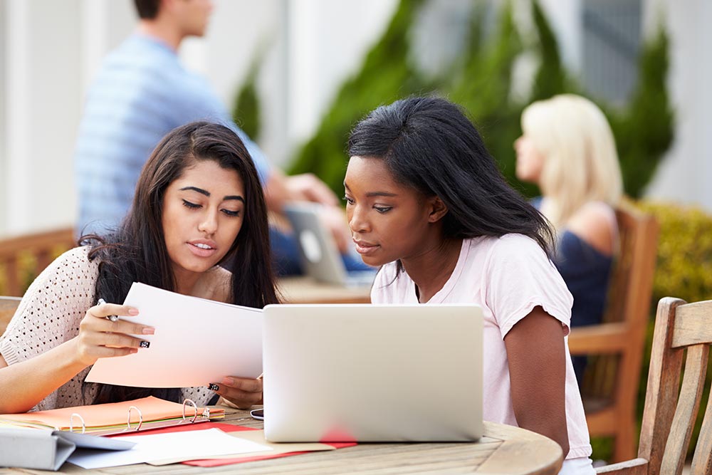 Two students plagiarising in a university - hybrid plagiarism detection is one of the most effective ways to detect this